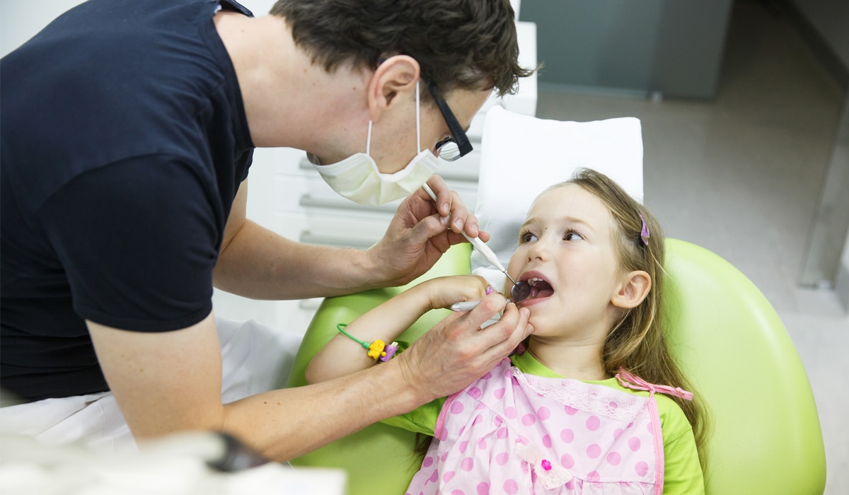 A dentist examining a young child's teeth.
