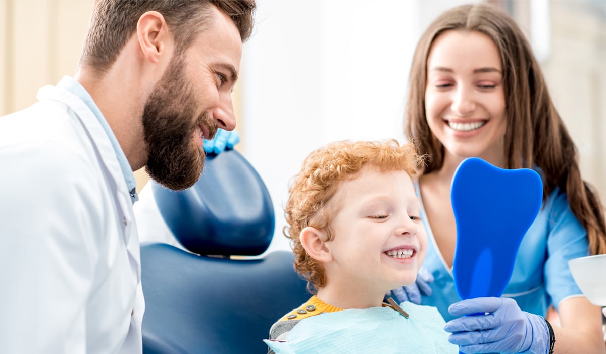 A child and parent discussing dental care with a dentist.