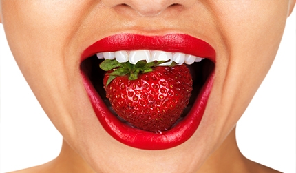 Close-up of a smile with a strawberry.